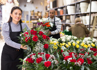 Florist in an apron creates bouquets in a flower shop