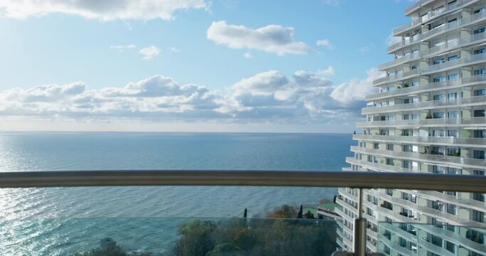 Hotel balcony view on Black sea calm ripple water and landscape under blue sky with floating clouds ON horizon at bright sunset light