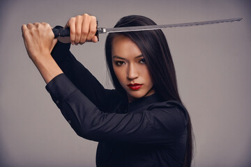 The way of the ninja. Studio portrait of a beautiful young woman in a martial arts outfit wielding...