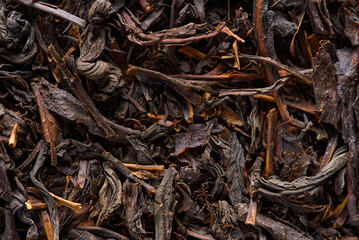 Black large-leaf tea as abstract background. Texture of dry black tea leaves. Dark background