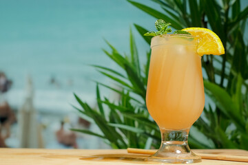 Beach bar concept. Drinking glass of orange punch cocktail with mint leaf and orange slice....