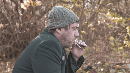 a poor homeless man with dirty hands smokes a cigarette in modern society. Economic recession, unemployment, poverty, hunger, pension, global crisis, the concept of the problem of inequality