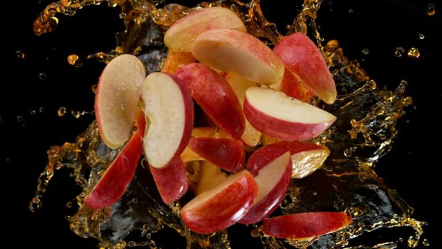 Super slow motion shot of rotating exploded red apple cuts and splashing Juice on black at 1000fps.