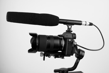 mirrorless camera and a connected microphone mounted on an electronic stabilizer on a white...