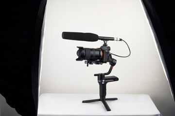 mirrorless camera and a connected microphone mounted on an electronic stabilizer on a white background
