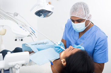 Male dentist treating female patient in dental office