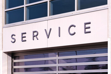 Service sign at car dealer building entrance with electrical operated roller shutter garage door....