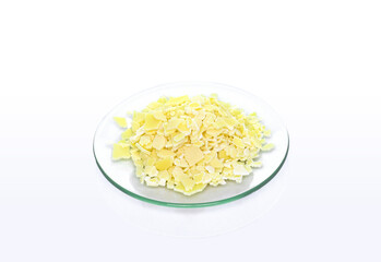 Closeup chemical ingredient on white laboratory table. Sodium sulfide flake in Chemical Watch Glass.