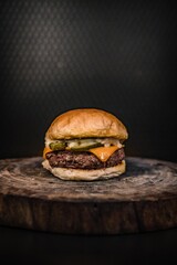 Foto de hamburguesa artesanal con fondo oscuro sobre tabla de madera