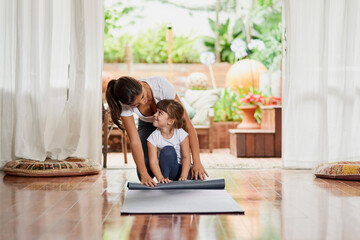 Teaching my daughter step by step. Shot of a cheerful young mother and daughter doing a yoga pose together while being seated on the ground.