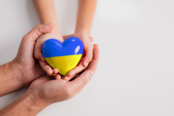 Family hands holding a heart in ucrainian colours on white background