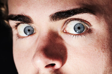 He saw a ghost. Closeup portrait of a young man with wide eyes and small pupils. - obrazy, fototapety, plakaty