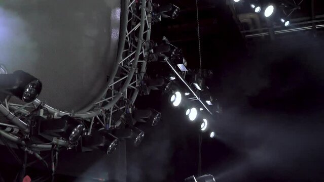 Camera tilts up from white stage lights to lighting rig on stage before a concert