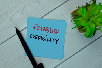 Establish Credibility write on sticky notes isolated on Wooden Table.
