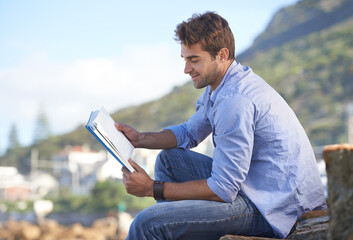 Novels are a great way to relax. A young man reading a book outdoors.
