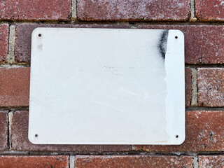Weathered urban white empty street sign on an industrial red brick wall detail 
