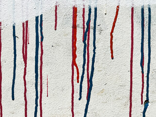 Blue and red graffiti spray paint runners on a white wall