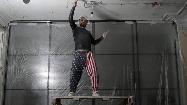 A happy builder on the background of a brick wall is dancing and enjoying the moment