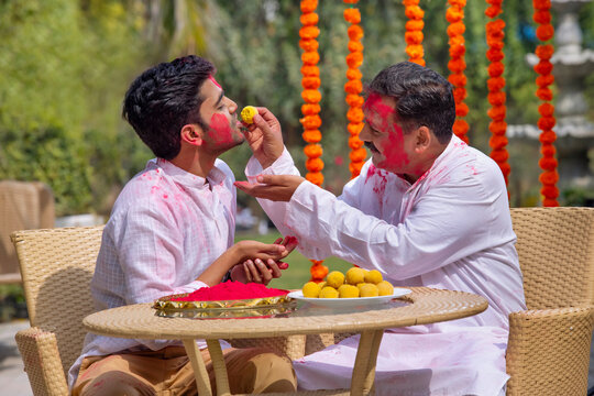 Father feeding ladoo to his son on the occasion of Holi
