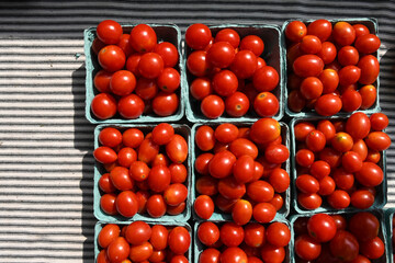 Fresh market garden tomatoes in cardboard box bowl on a stripped table cloth 