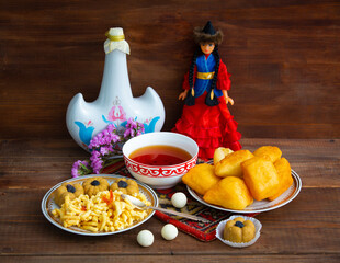 Kazakh still life on Nauryz, with national food: baursaks, zhent, kurt, chak chak and tea on a wooden background