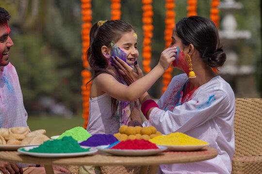 Young couple with their daughter celebrating Holi together 
