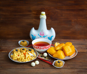 Kazakh still life on Nauryz, with national food: baursaks, zhent, kurt, chak chak and tea on a wooden background