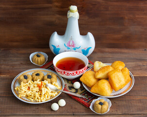 Kazakh still life on Nauryz, with national food: baursaks, zhent, kurt, chak chak and tea on a wooden background