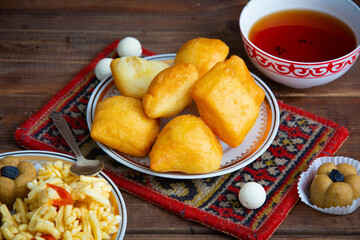 Kazakh still life on Nauryz, with national food: baursaks, zhent, kurt, chak chak and tea on a wooden background