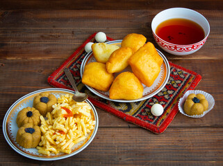 Kazakh still life on Nauryz, with national food: baursaks, zhent, kurt, chak chak and tea on a wooden background