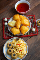 Kazakh still life on Nauryz, with national food: baursaks, zhent, kurt, chak chak and tea on a wooden background