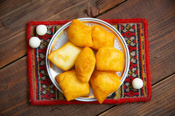 Kazakh still life on Nauryz, with national food: baursaks, zhent, kurt, chak chak and tea on a wooden background