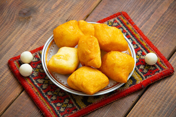 Kazakh still life on Nauryz, with national food: baursaks, zhent, kurt, chak chak and tea on a wooden background