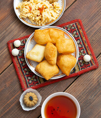 Kazakh still life on Nauryz, with national food: baursaks, zhent, kurt, chak chak and tea on a wooden background