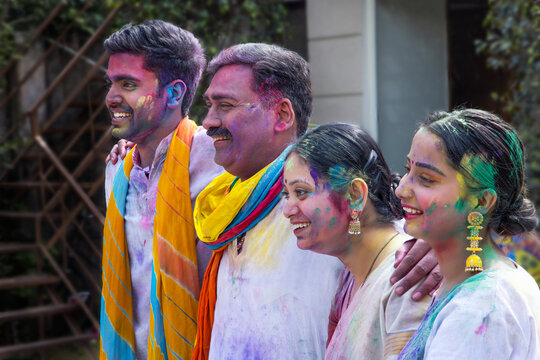 Happy family members standing in line with putting their hands on each other's shoulders and looking at the camera with smiling faces on Holi