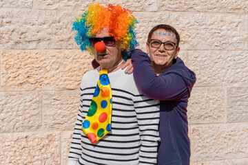 Funny senior couple dressed up for Halloween or Purim or birthday party. Funny old man in a clown...