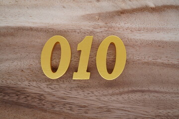 Golden Arabic numerals on a real brown and white wooden floor number 010