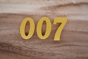 Golden Arabic numerals on a real brown and white wooden floor number 007