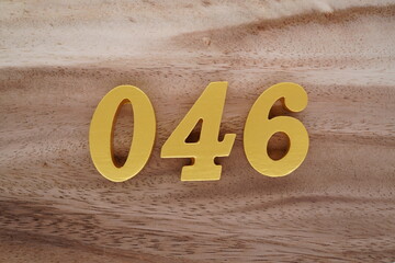 Golden Arabic numerals on a real brown and white wooden floor number 046