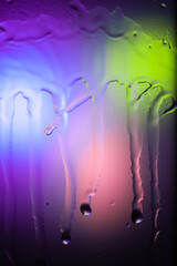 drops and splashes of water spreading on glass on a bright colored background