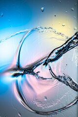 drops and splashes of water spreading on glass on a bright colored background