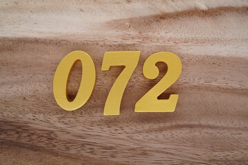 Golden Arabic numerals on a real brown and white wooden floor number 072