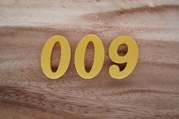 Golden Arabic numerals on a real brown and white wooden floor number 009