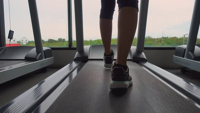 Close up sports shoes woman muscular legs feet during running on treadmill workout in the morning time at fitness gym, Jogging shoes for walking on a treadmill she exercises on cardio