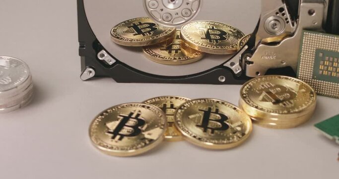 Gold BTC coins reflecting on silver disc of Hard Drive platter. Cryptocurrency concept, storage of Blockchain on Hard Drive disc