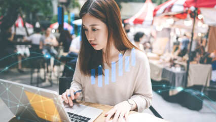 Adult asian woman working at outdoor cafe laptop computer show a financial stock market increase...