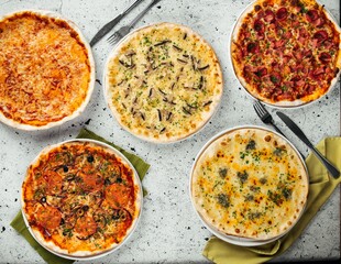 Top view on different freshly baked pizzas on the table