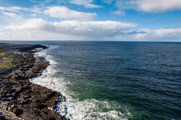 Fototapeta na wymiar Rough stone coastline and blue ocean surface, cloudy sky. West coast of Ireland. Burren area. Nobody. Aerial view.