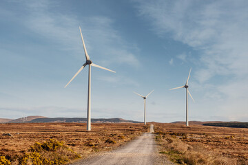 High wind power turbine in a field. Cloudy sky background. Renewable green energy production, source of clean electric supply. Modern technology and design. Nobody.