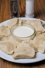 Serving of polish dumplings with small bowl of sour cream, close up. Traditional simple food.